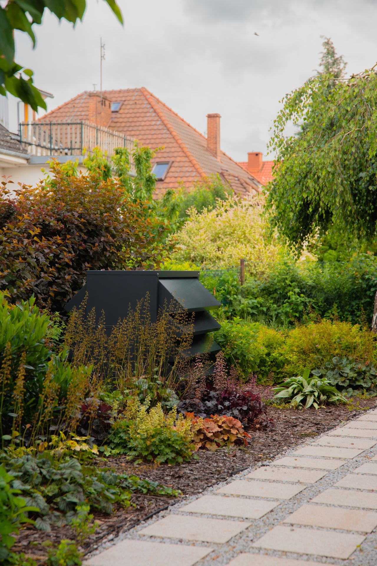 heat pump in the garden surrounded by greenery with a soundproof acoustic enclosure for the heat pump