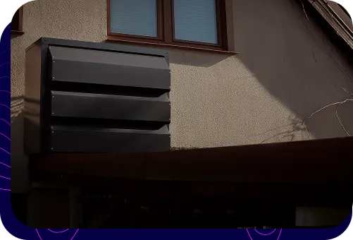 A modern, dark Silencions s|AC| acoustic enclosure mounted on the wall of a residential building, covering the outdoor unit of an air conditioner.