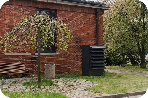 The modern Silencions s|HP| acoustic enclosure against the backdrop of a brick residential building, ensuring quiet and an aesthetic appearance in the neighbourhood.