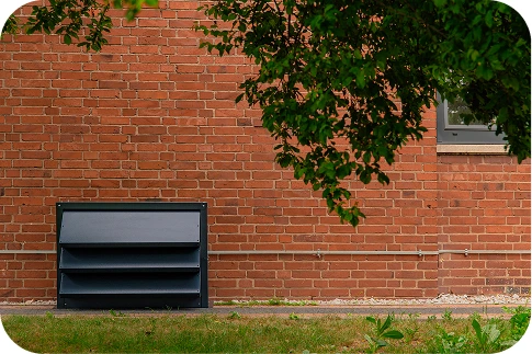 A modern hotel building with a silent heat pump surrounded by greenery, emphasising quiet and aesthetic solutions for the hotel industry.