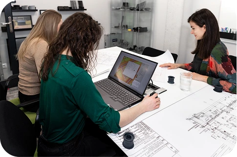 The Silencions team of experts – three people sitting at a table analysing technical plans and acoustic simulation results on a laptop screen.