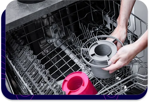 Photo showing how s|TWIST sound absorbers are placed in the dishwasher. Hands place one of the absorbers in the basket, demonstrating that the product is waterproof and can be washed mechanically, ensuring easy maintenance.