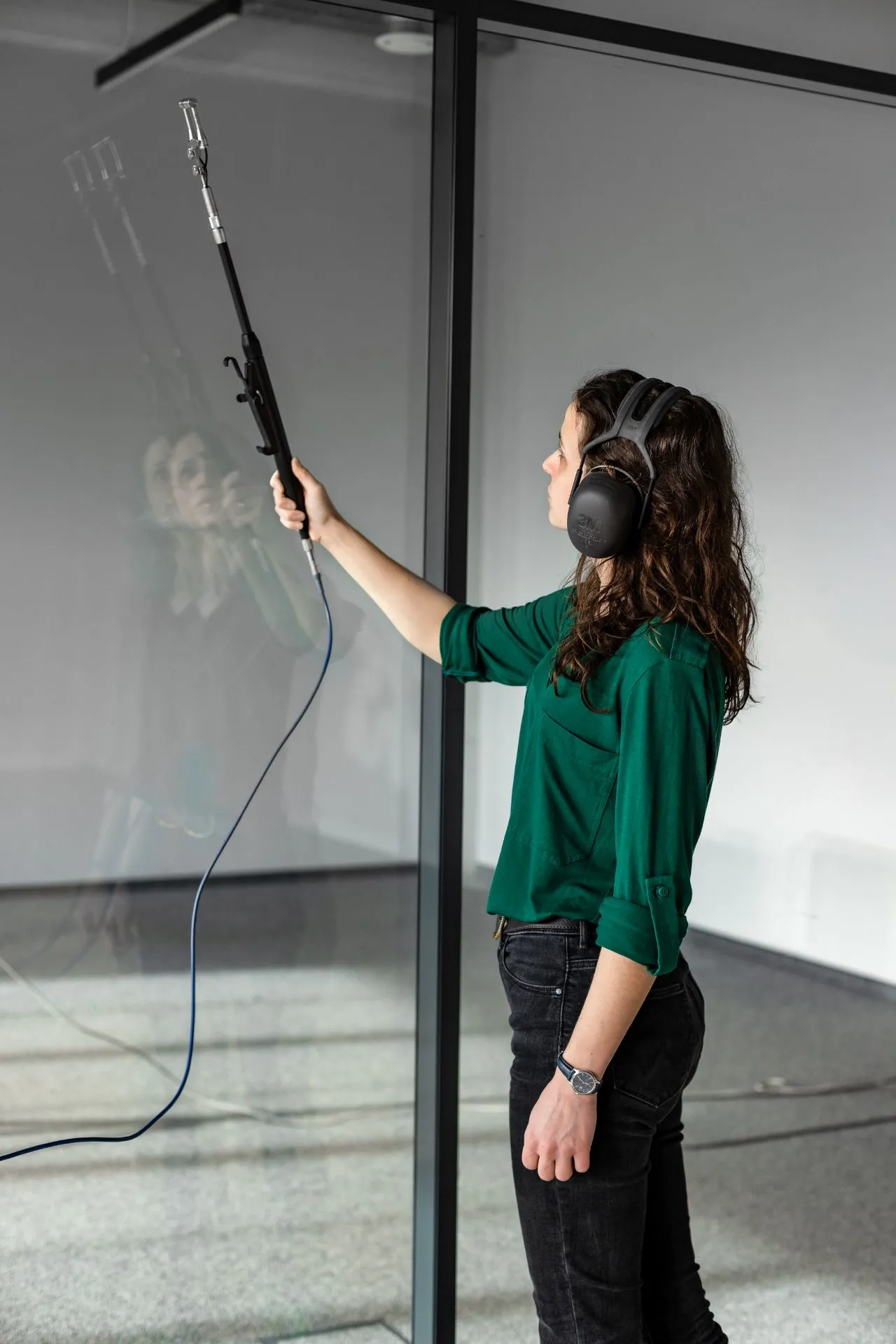 A Silencions engineer measures the acoustic insulation of a glass wall in a modern office.