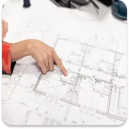 A hand pointing to a fragment of project documentation or architectural plans, symbolising the stage of analysis and planning of the action strategy before the commencement of the acoustic survey.