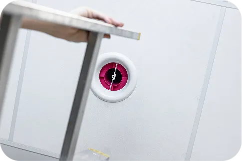 Photo illustrating the installation of a pink s|Twist sound absorber in a ceiling ventilation grille.