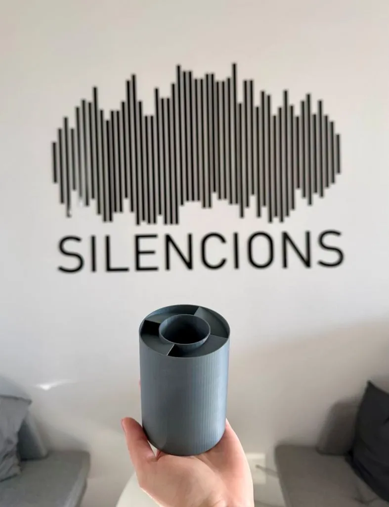 s|TWIST| acoustic silencer held in hand against the Silencions logo background — a modern noise reduction solution for cable penetrations.