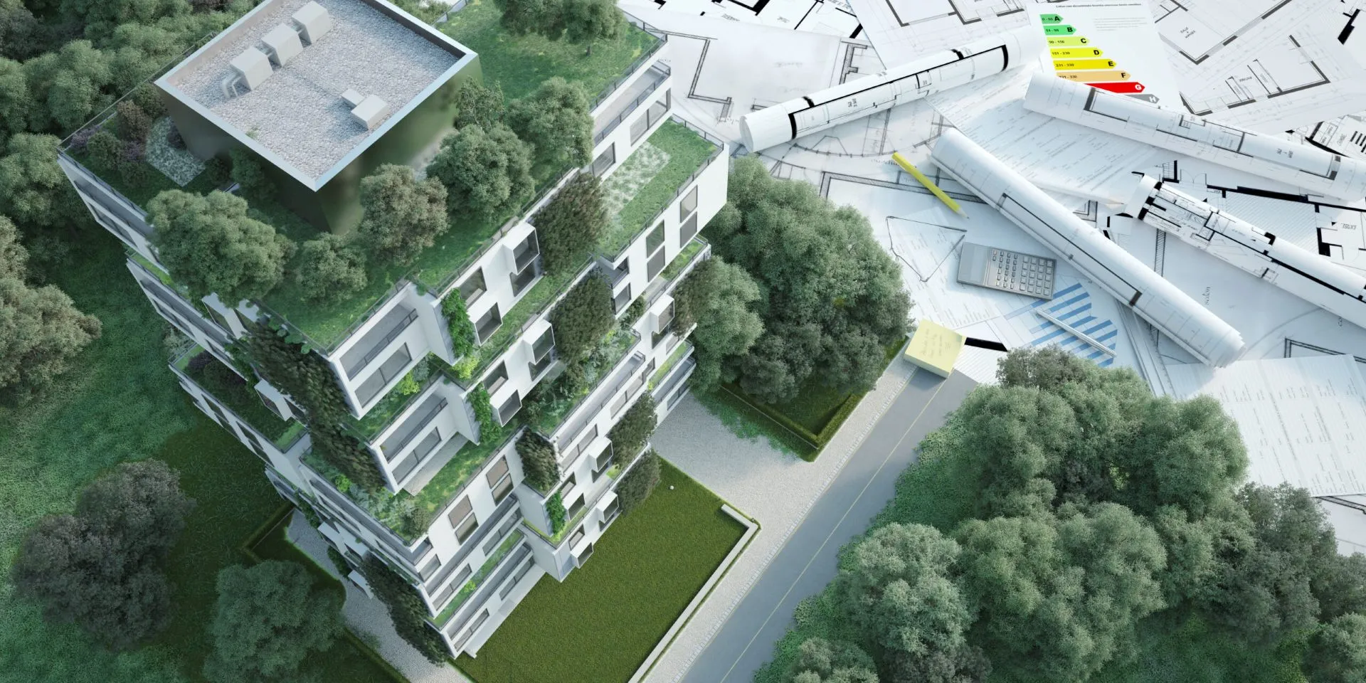 A top-down view of a modern housing estate with green roofs and facades. Next to the building are architectural plans, a roll of paper, a calculator, and energy efficiency charts.
